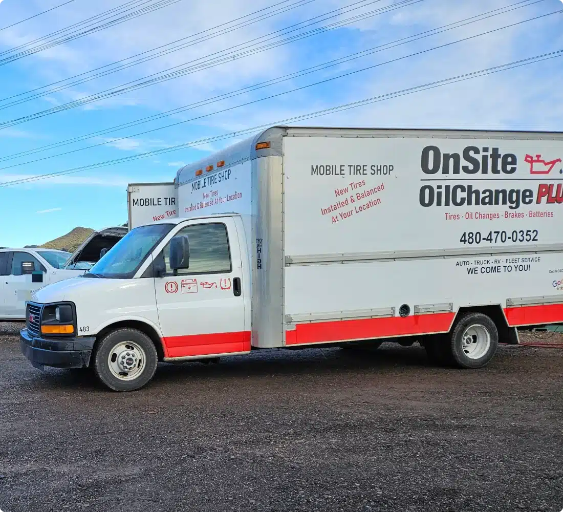 A white service truck with red accents displays OnSite Oil Change Plus and Mobile Tire Shop on the side, advertising mobile auto repair, tire, and oil change services. Another similar truck is partially visible in the background.