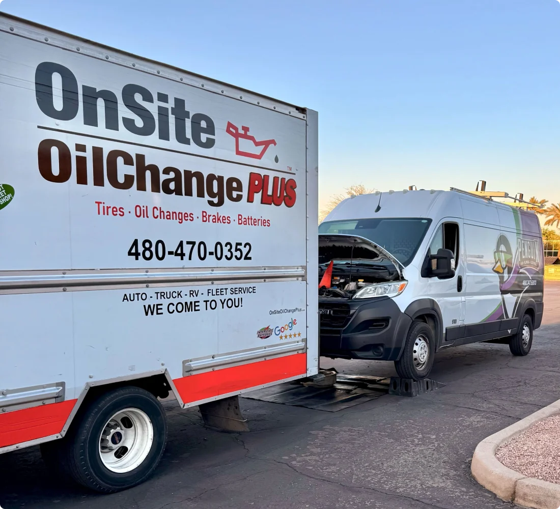 A mobile oil change service van with its hood open is parked next to a trailer labeled OnSite Oil Change PLUS, which offers tires, oil changes, brakes, and batteries. Learn more about their services by calling the visible phone number.
